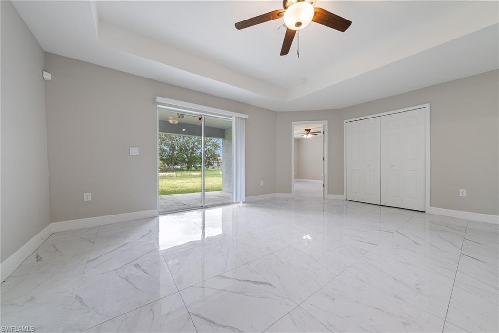 Unfurnished bedroom with a raised ceiling, access to exterior, a ceiling fan, and a closet