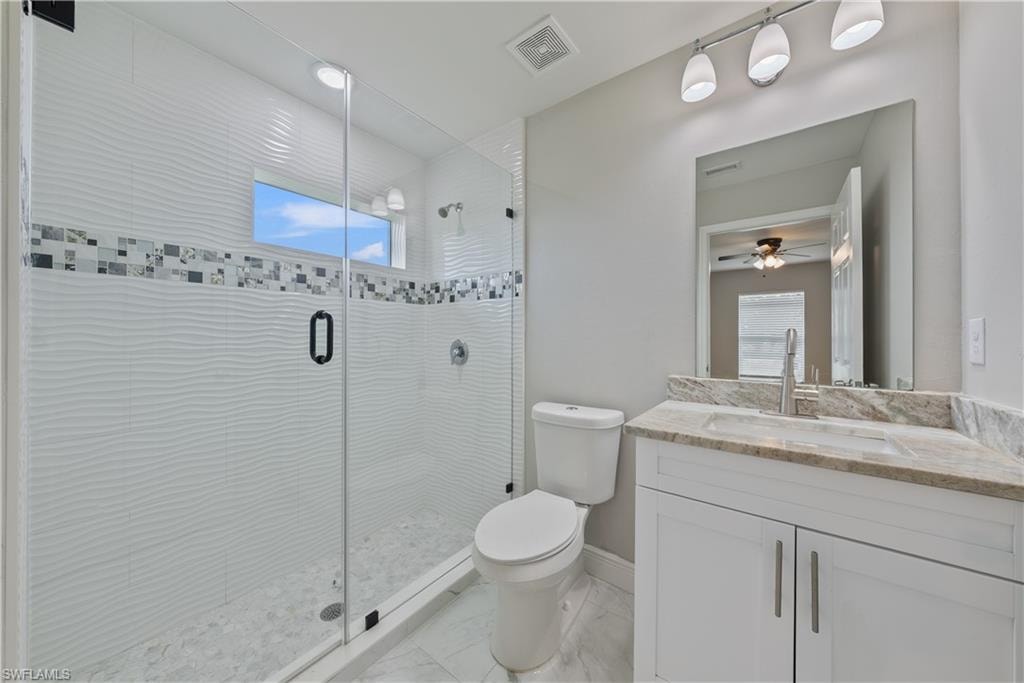 Full bathroom featuring vanity, a stall shower, ceiling fan, and healthy amount of natural light