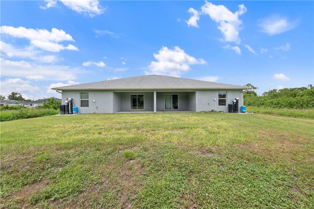 Back of property featuring a yard, stucco siding, and a patio area