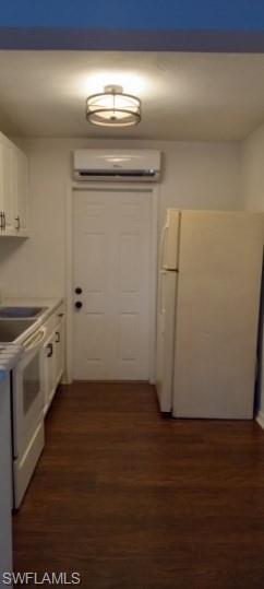 Kitchen featuring white appliances, white cabinets, dark wood-type flooring, and light countertops