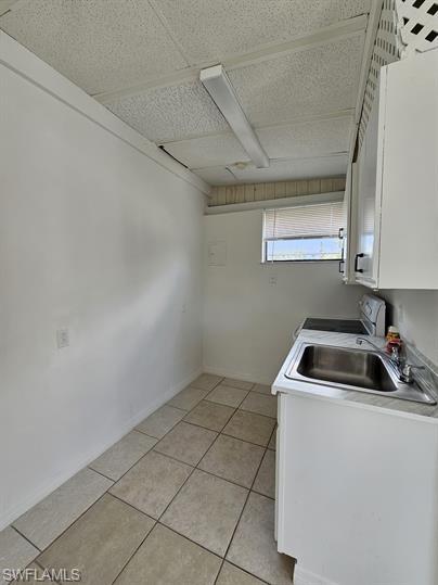 Laundry room with light tile patterned floors and a paneled ceiling