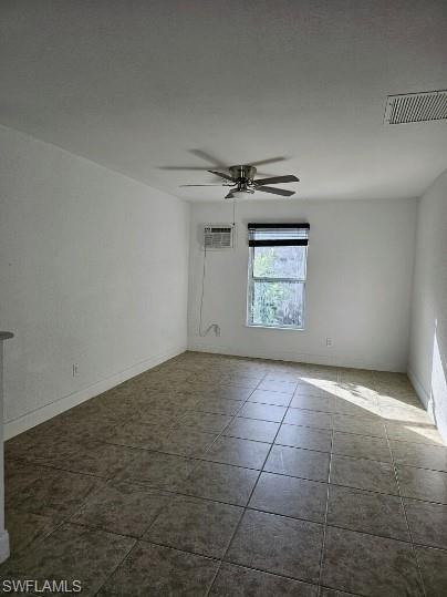 Tiled empty room with ceiling fan and baseboards
