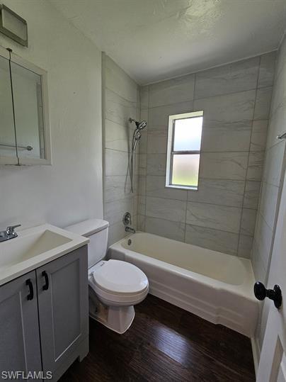 Bathroom with shower / bath combination, vanity, and dark wood-style flooring