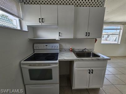 Kitchen featuring white range with electric stovetop, light countertops, white cabinetry, and light tile patterned floors