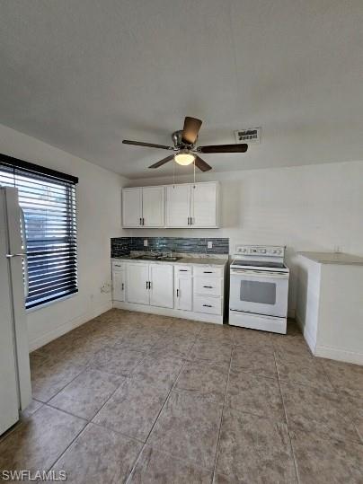 Kitchen featuring white cabinets, white appliances, and ceiling fan