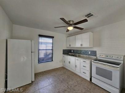 Kitchen with white appliances, white cabinets, ceiling fan, light tile patterned floors, and light countertops