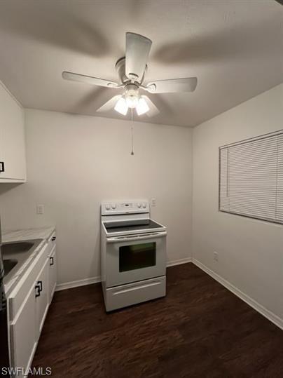 Kitchen featuring electric stove, white cabinets, light countertops, dark wood-type flooring, and ceiling fan
