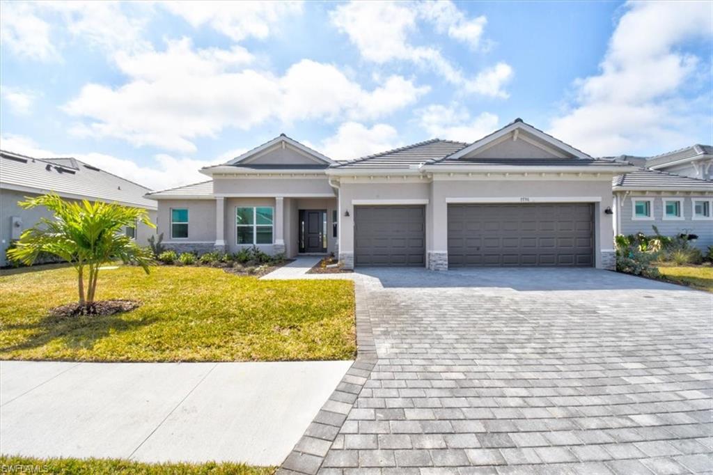 View of front of house with a front yard, stucco siding, decorative driveway, and an attached garage