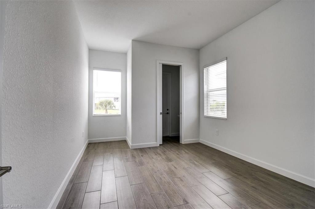 Unfurnished bedroom featuring wood finished floors, multiple windows, and a textured wall