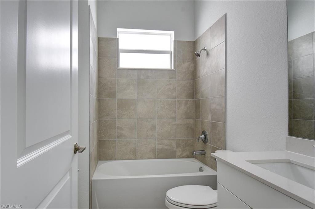 Full bath featuring a textured wall, shower / bathtub combination, and vanity