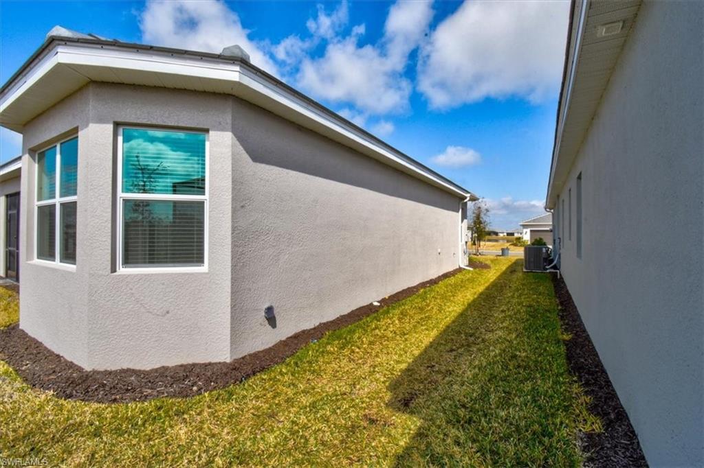 View of side of home with stucco siding and a yard