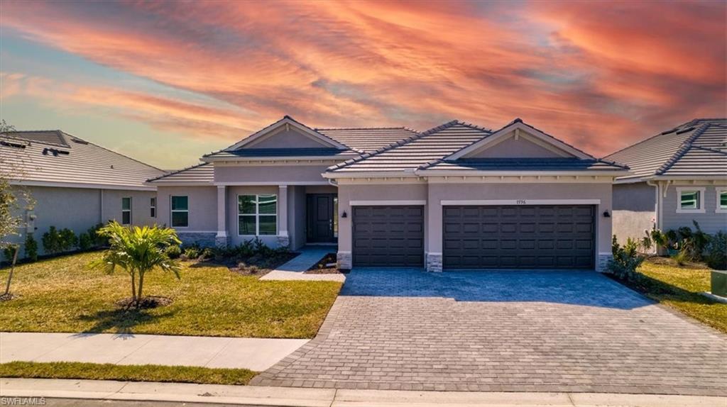View of front of home featuring stucco siding, a yard, and decorative driveway