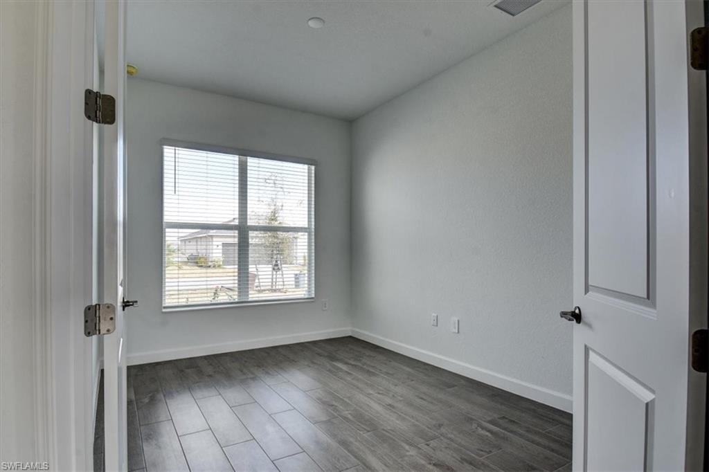 Empty room with dark wood-style flooring and baseboards