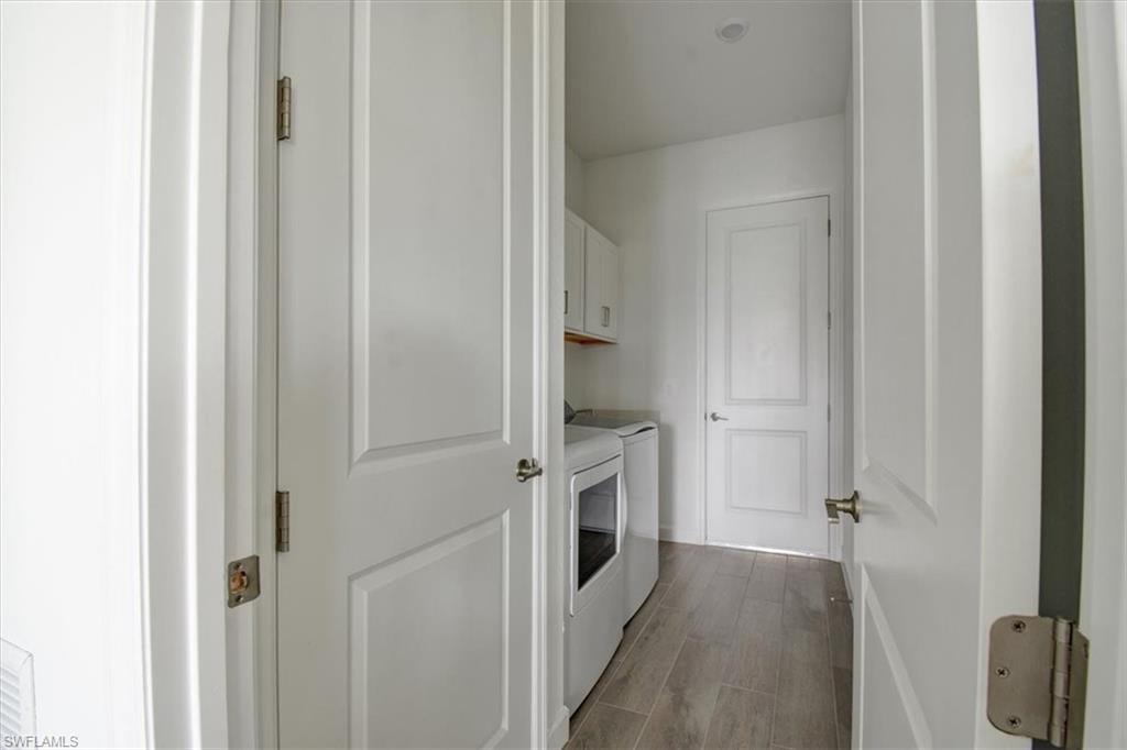 Laundry room featuring dark wood-style floors, cabinet space, and washer and dryer