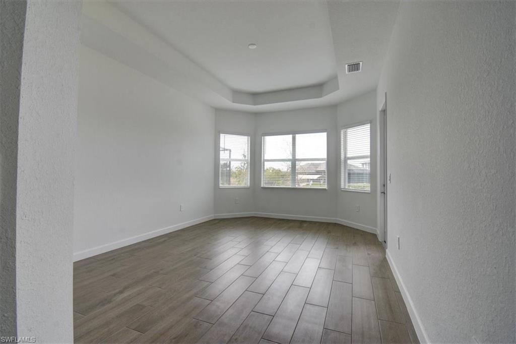 Unfurnished room featuring wood tiled floors, a textured wall, and a raised ceiling