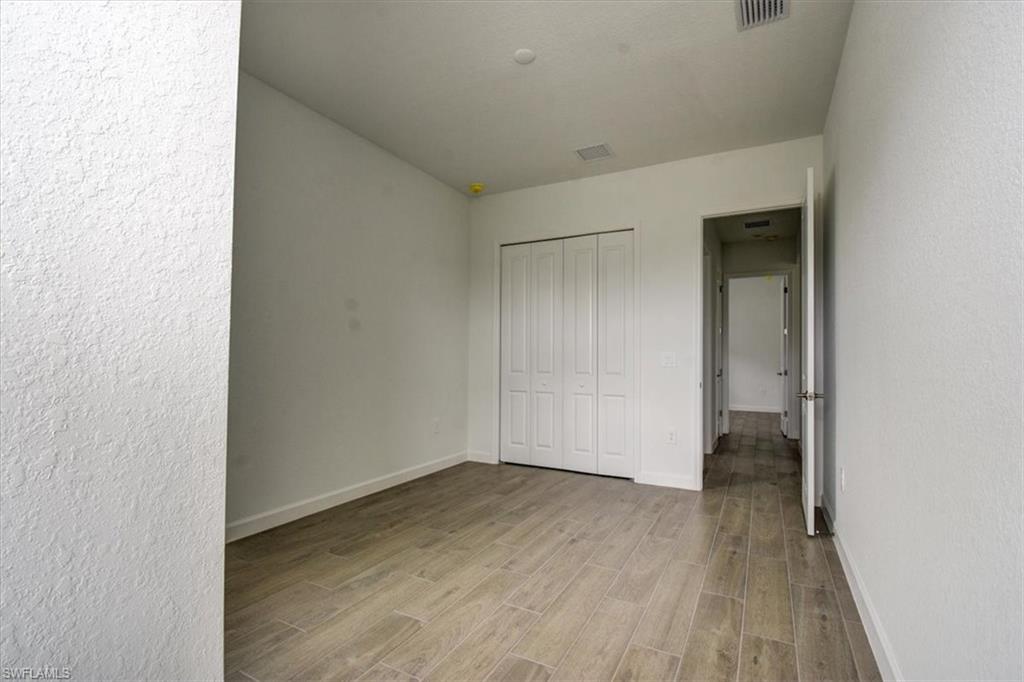 Unfurnished bedroom with wood finish floors, a textured wall, and a closet