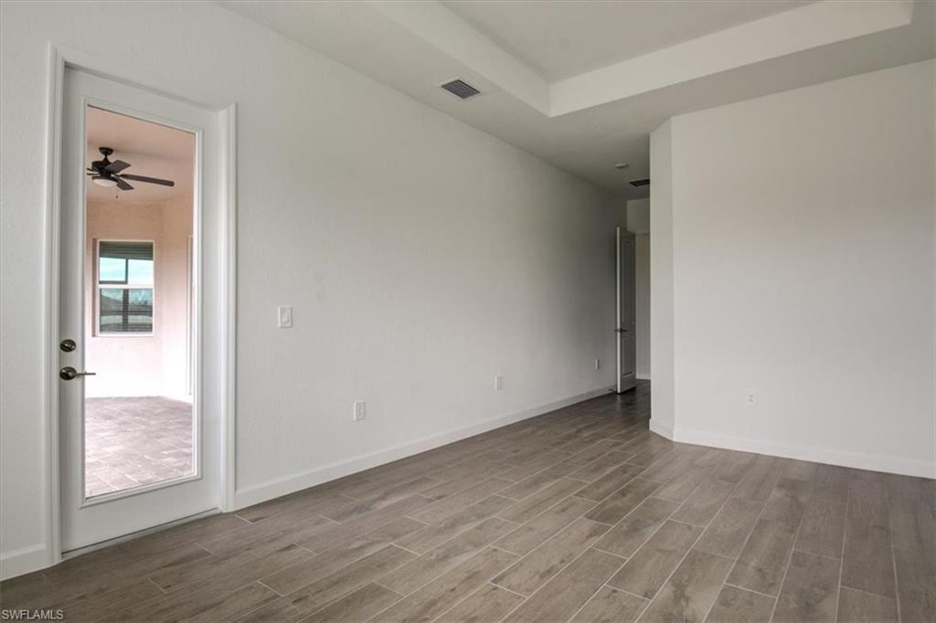 Spare room featuring a raised ceiling, wood finish floors, and a ceiling fan