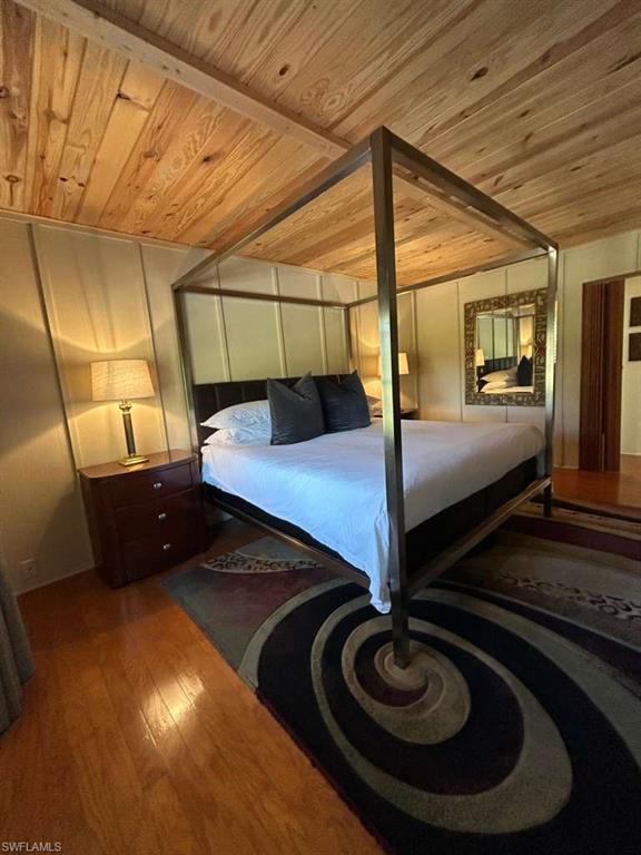 Bedroom featuring dark wood-type flooring and a wood ceiling with exposed beams