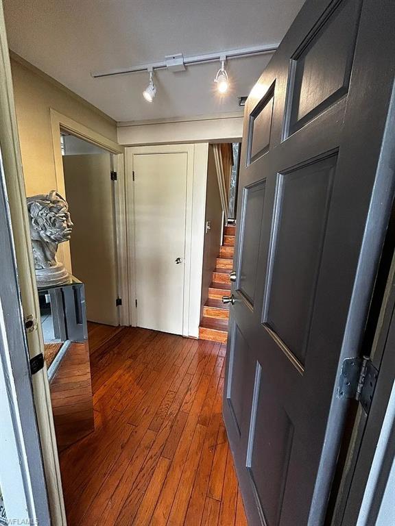 Foyer featuring rail lighting, stairway, and wood finished floors