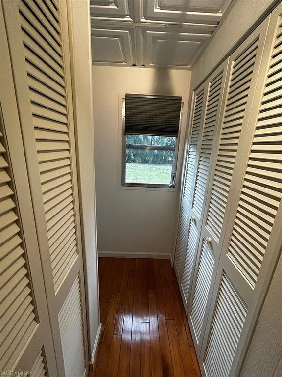 Hallway featuring dark wood-type flooring and baseboards