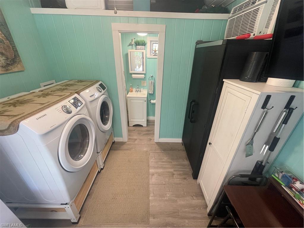 Laundry area featuring washing machine and dryer, light wood finished floors, and wood walls