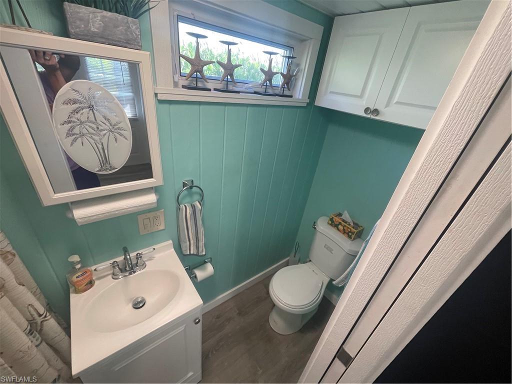 Half bathroom featuring vanity, dark wood-style floors, and wooden walls