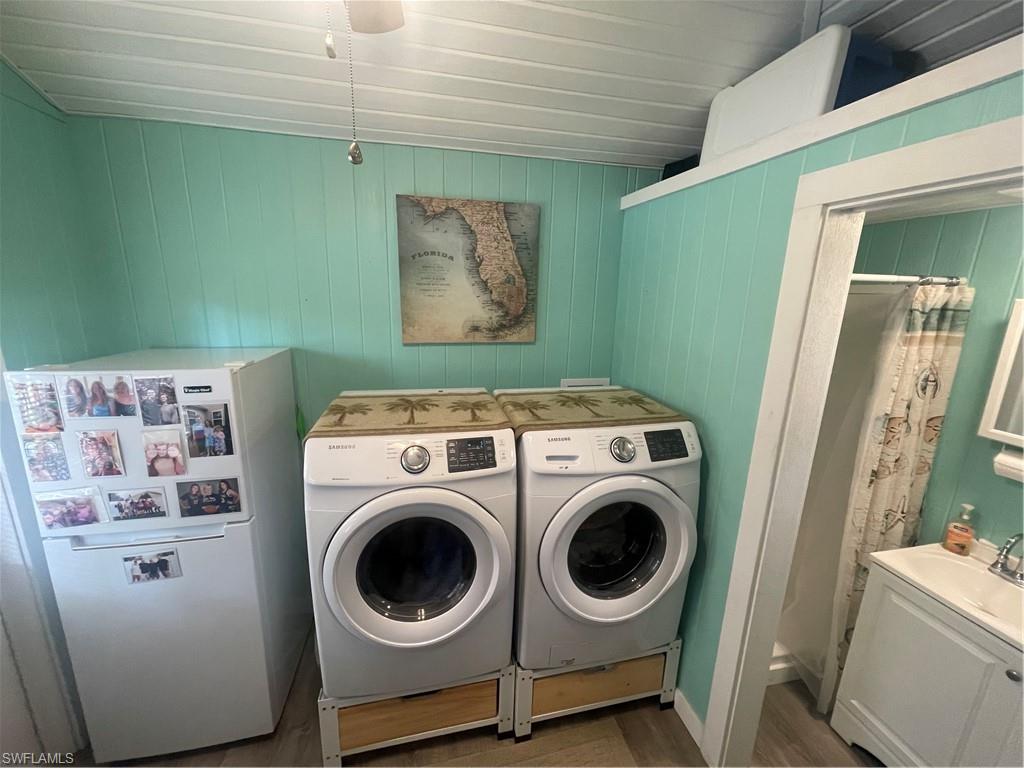 Laundry area featuring independent washer and dryer, wood walls, and wood finished floors