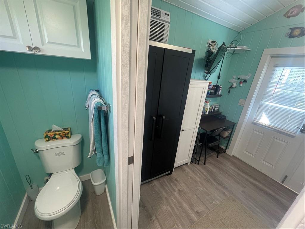 Bathroom featuring wooden walls, vaulted ceiling, and light wood-style floors