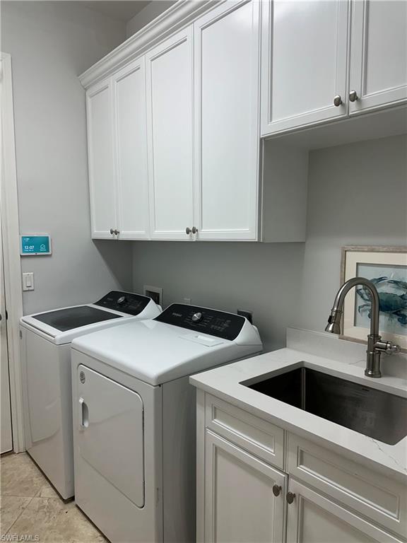 Laundry area with washing machine and dryer, cabinet space, and a sink