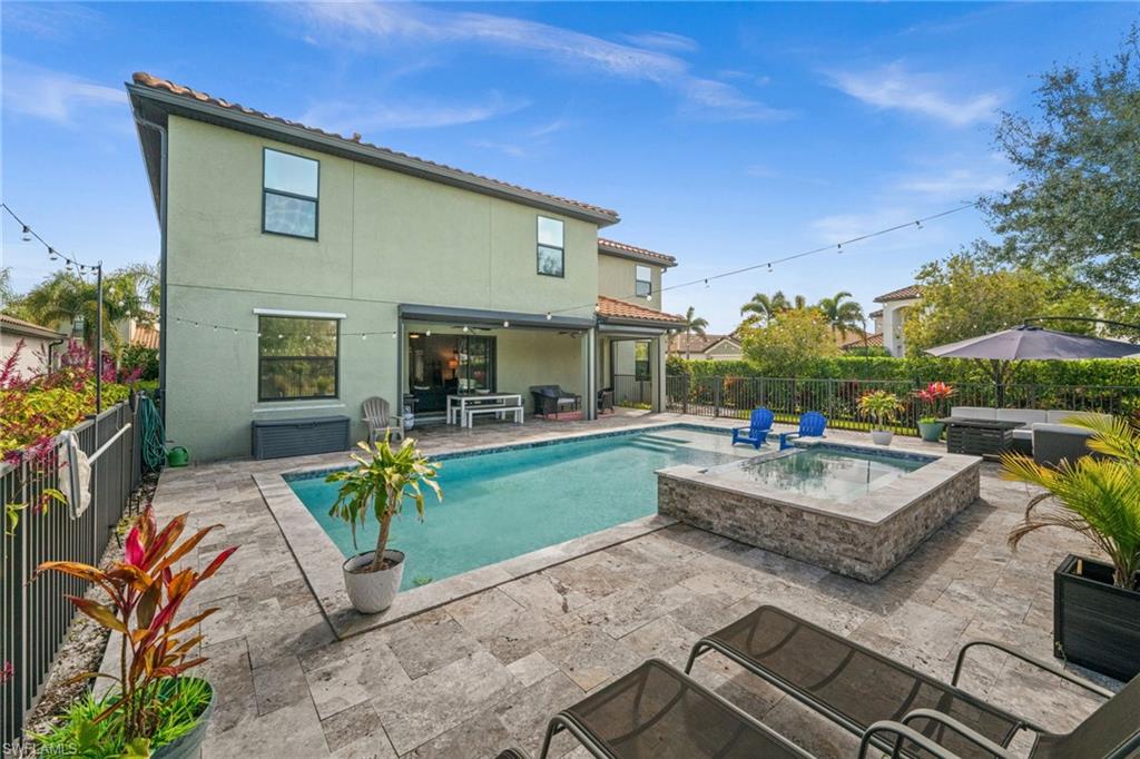 Back of property with pool, spa, large deck and a tile roof