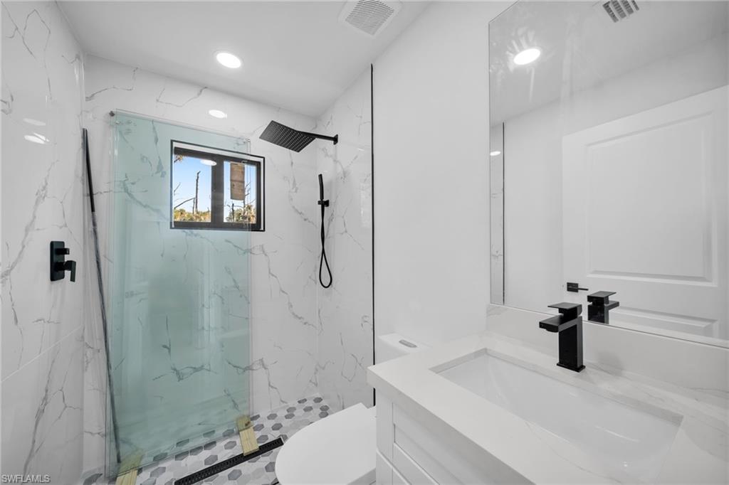 Bathroom featuring vanity, a marble finish shower, and recessed lighting