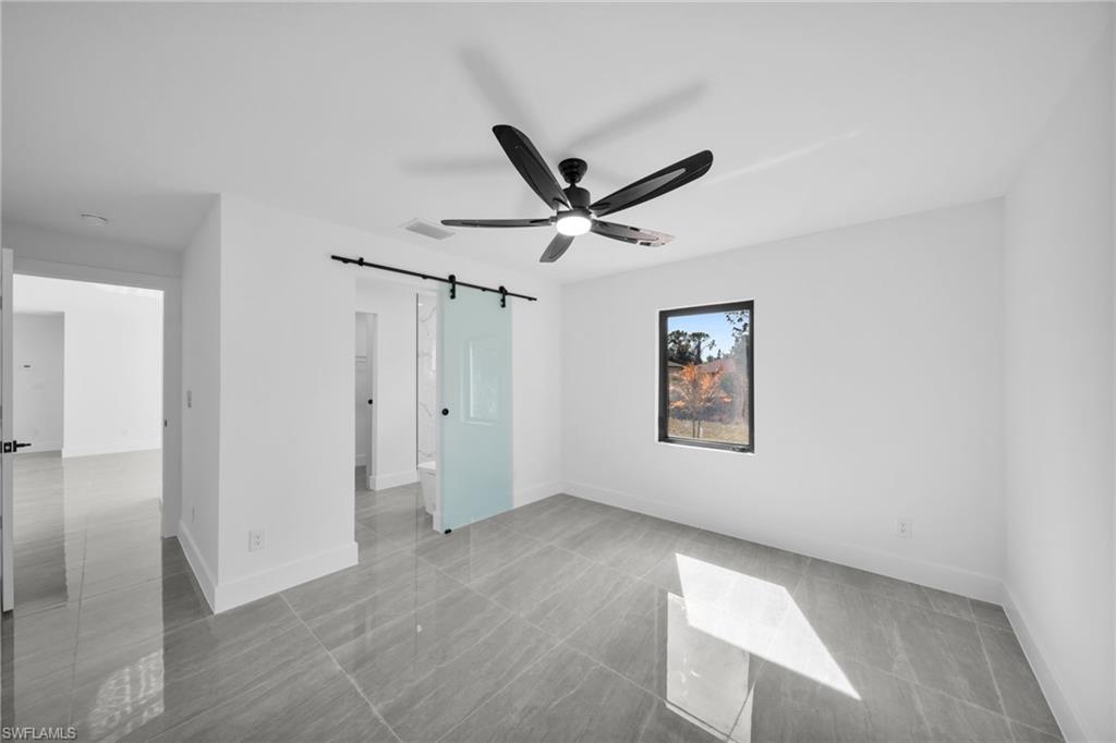 Unfurnished bedroom featuring a barn door and a ceiling fan