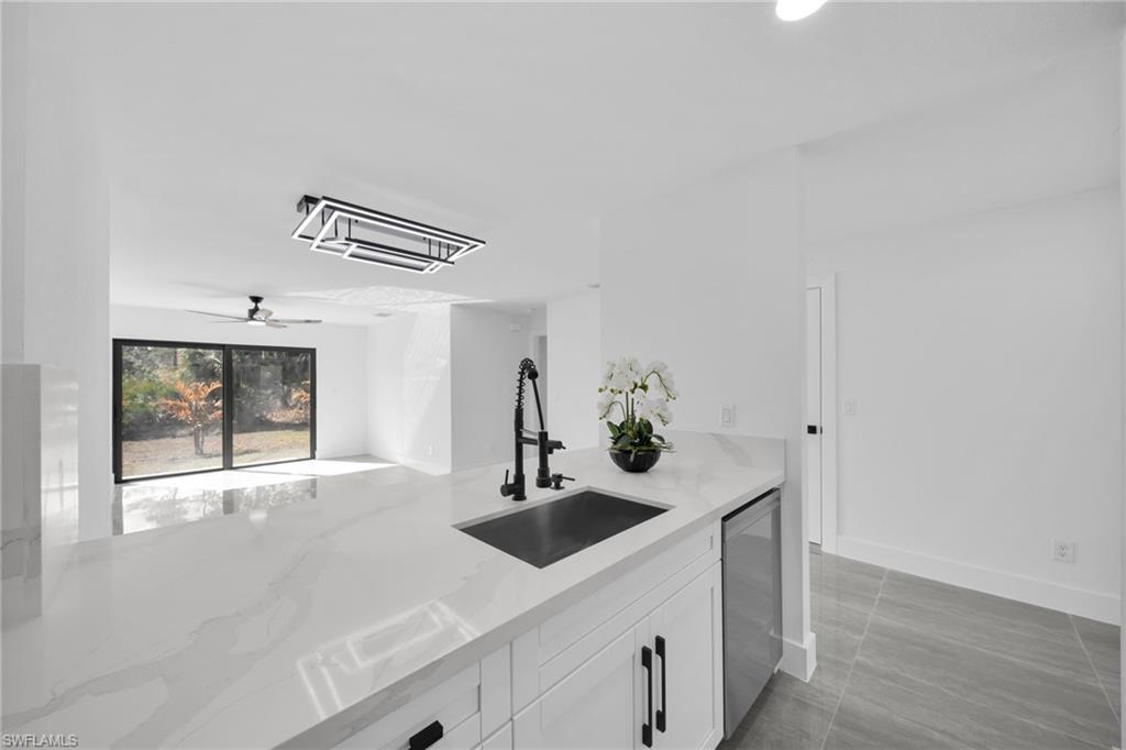 Bar with white cabinets, light stone counters, cooling unit, ceiling fan, and dishwasher