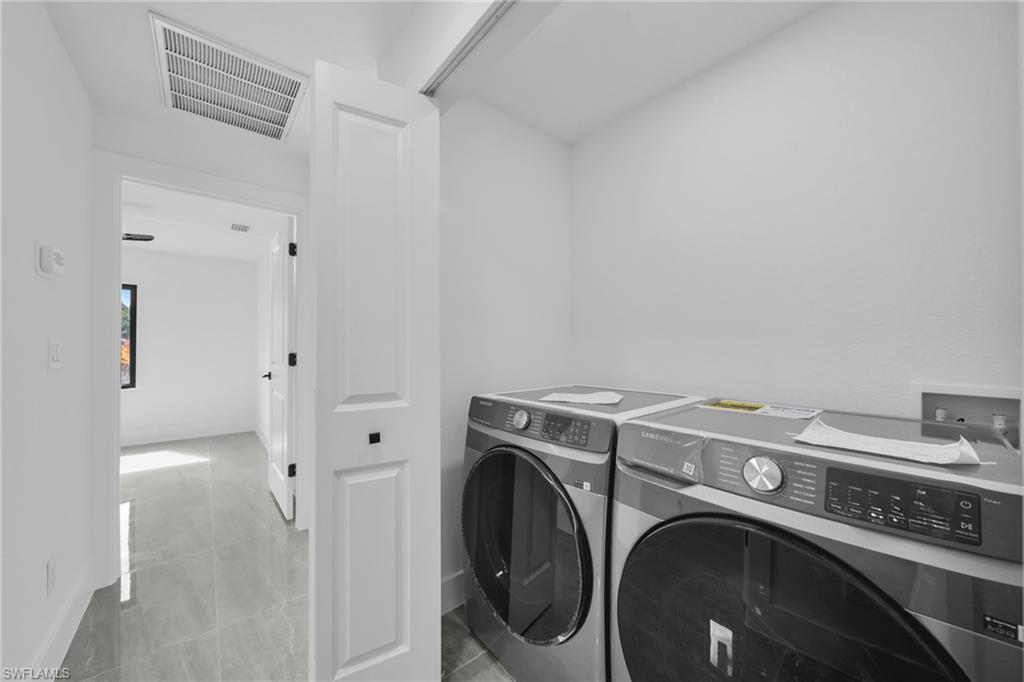 Laundry area with independent washer and dryer and light tile patterned flooring