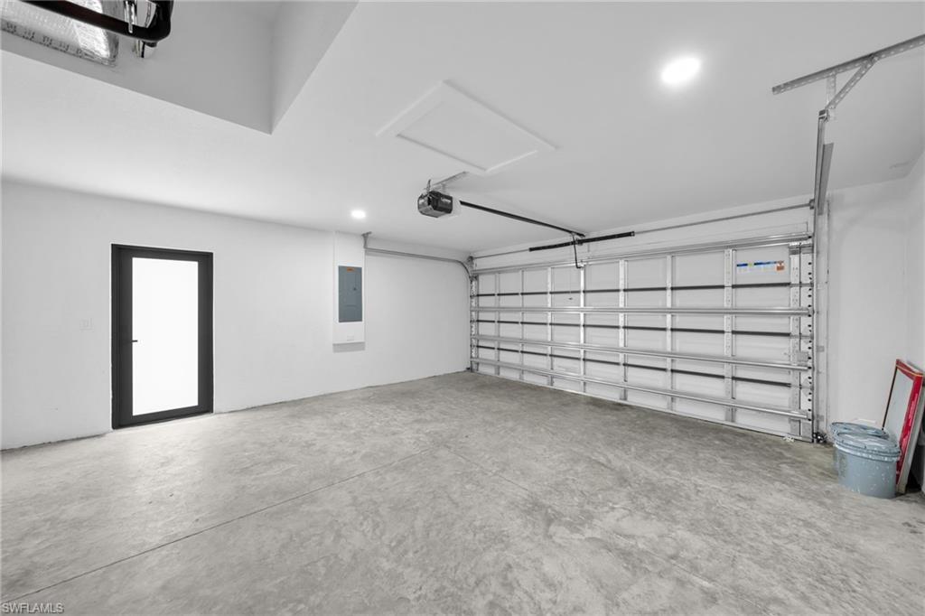 Garage featuring recessed lighting, electric panel, and a garage door opener