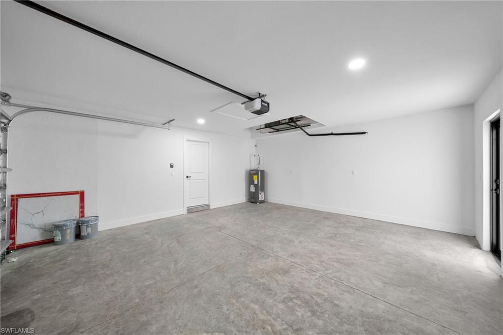 Garage featuring recessed lighting, water heater, and a garage door opener