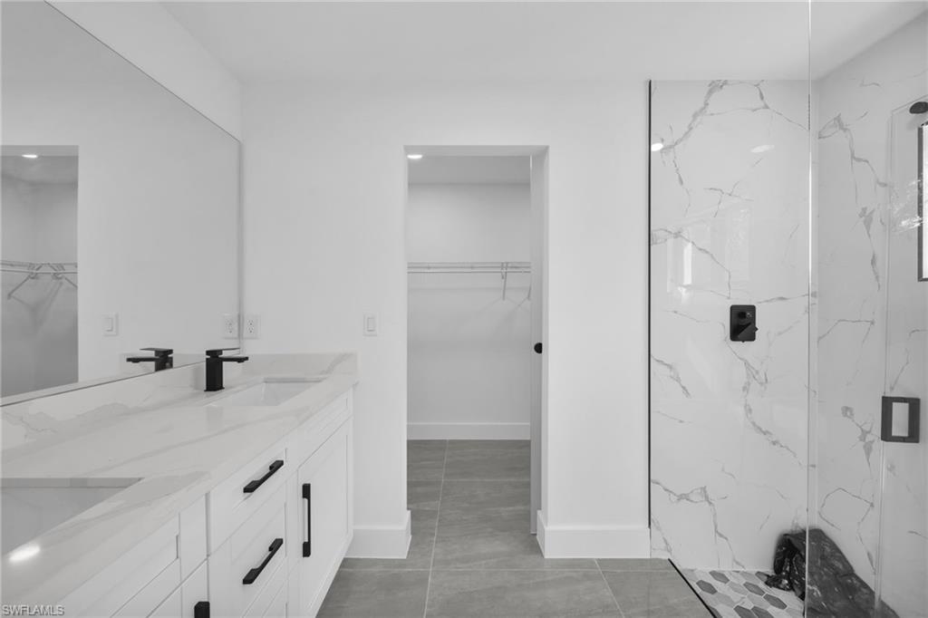 Full bathroom with a spacious closet, a marble finish shower, and double vanity