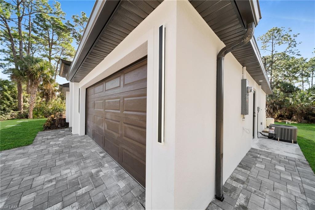 View of side of property featuring stucco siding, a patio area, driveway, and a yard