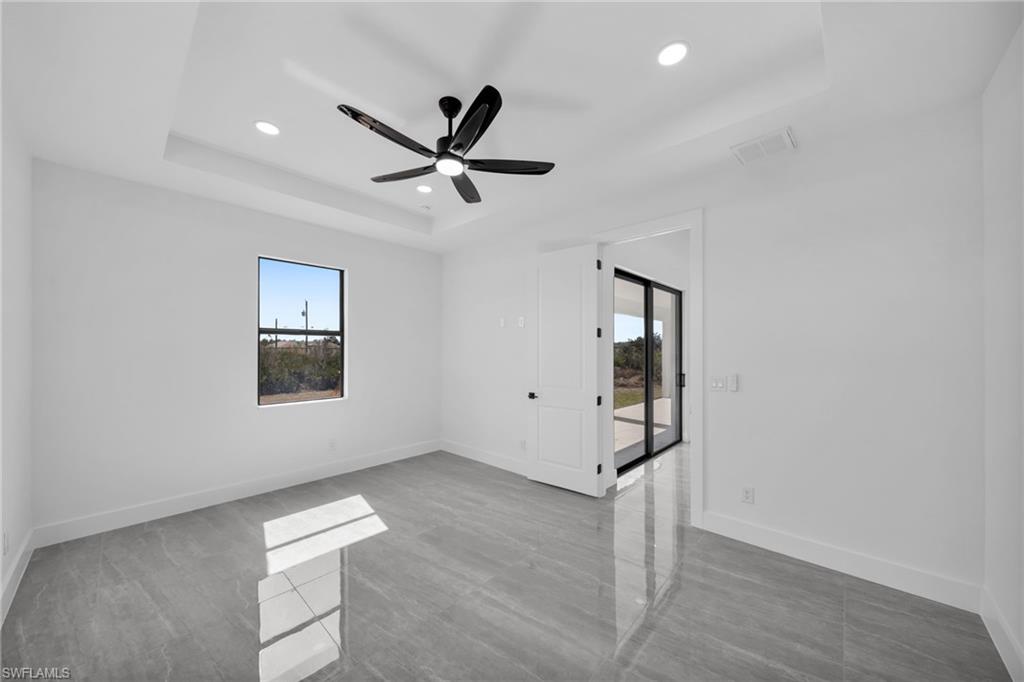 Unfurnished room featuring plenty of natural light, a tray ceiling, ceiling fan, and recessed lighting