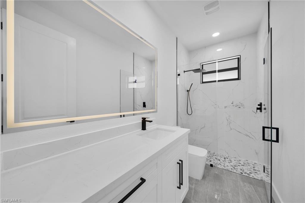 Full bathroom featuring a marble finish shower, vanity, and recessed lighting