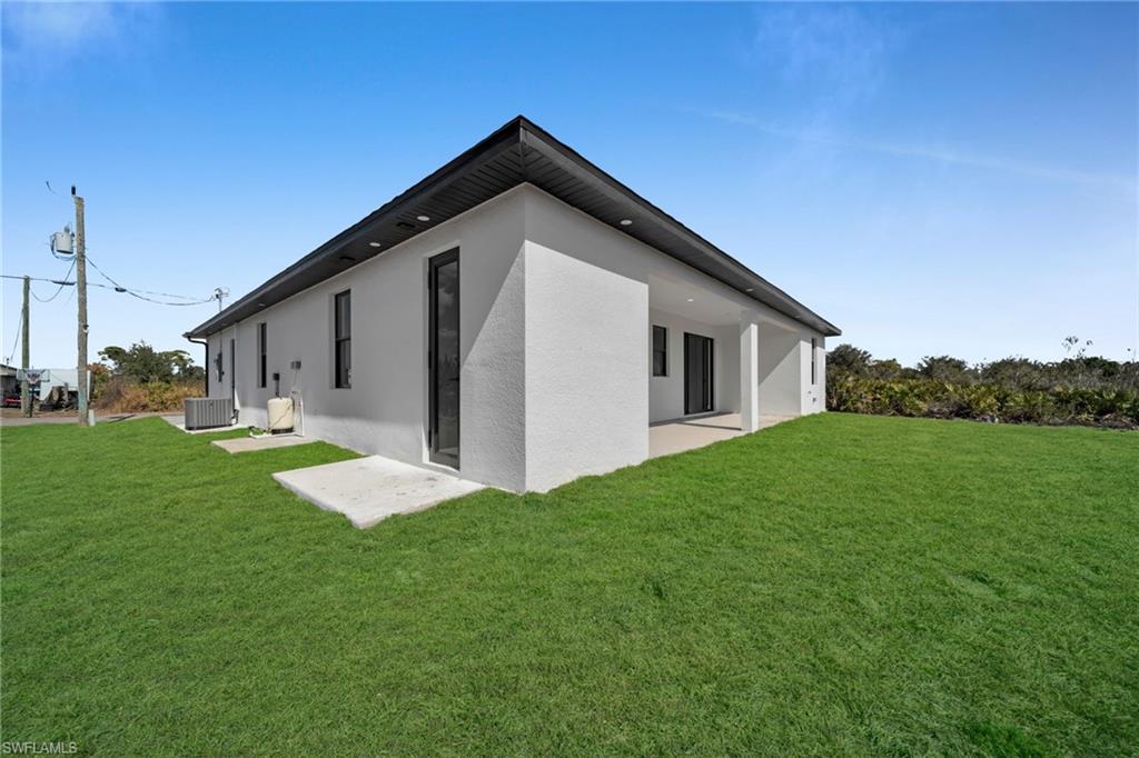 Back of house featuring a lawn, stucco siding, and a patio
