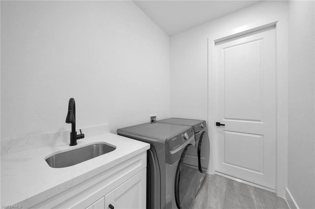 Laundry area with independent washer and dryer, light wood-style floors, and cabinet space
