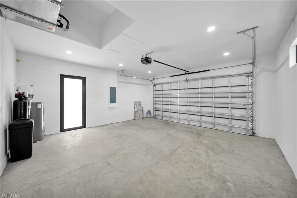 Garage featuring recessed lighting, electric panel, water heater, and a garage door opener