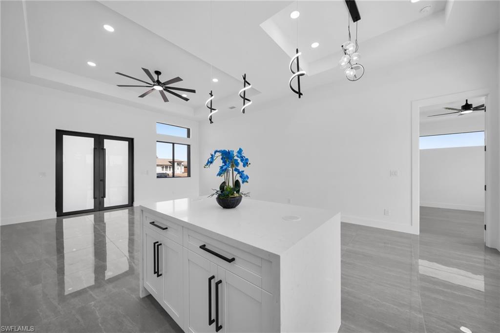 Kitchen featuring a ceiling fan, a tray ceiling, open floor plan, white cabinetry, and a kitchen island