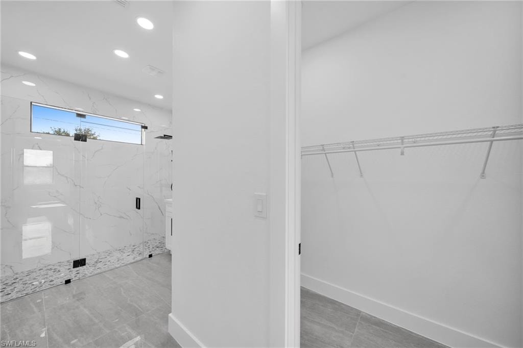 Bathroom featuring a walk in closet, a marble finish shower, and recessed lighting