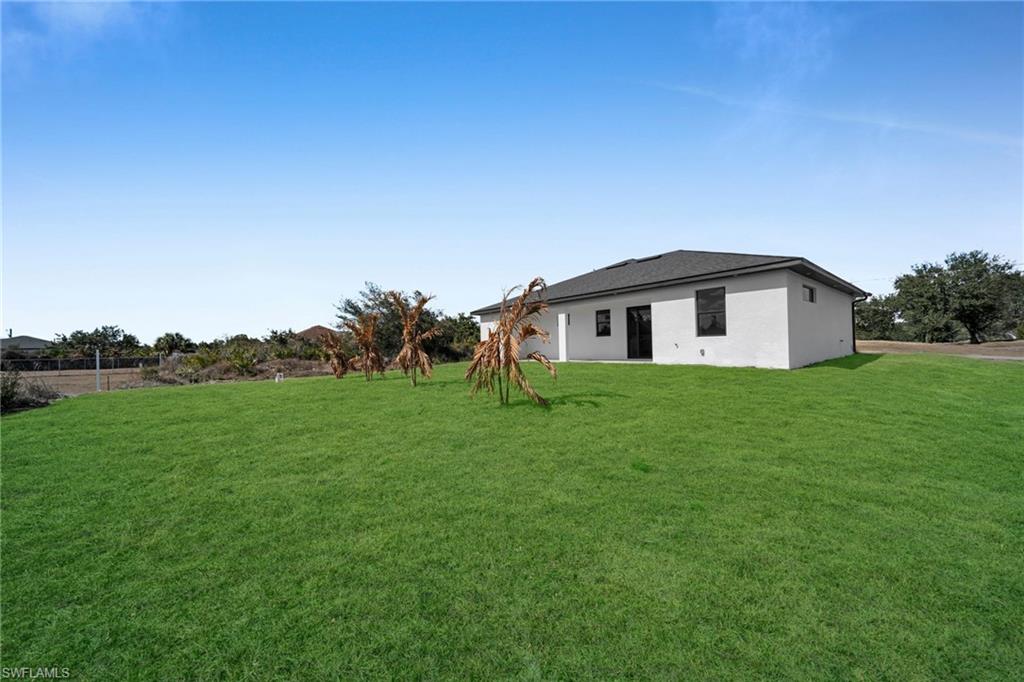 Rear view of property with a yard and stucco siding