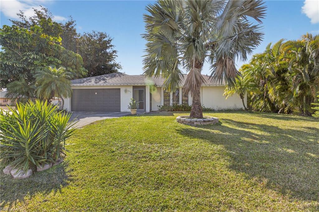 Ranch-style house featuring stucco siding, a front lawn, an attached garage, and driveway