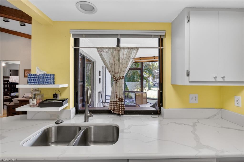 Kitchen featuring light stone counters and white cabinetry