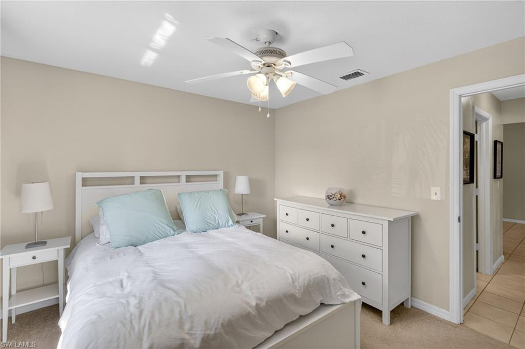 Bedroom with light colored carpet, a ceiling fan, and light tile patterned floors