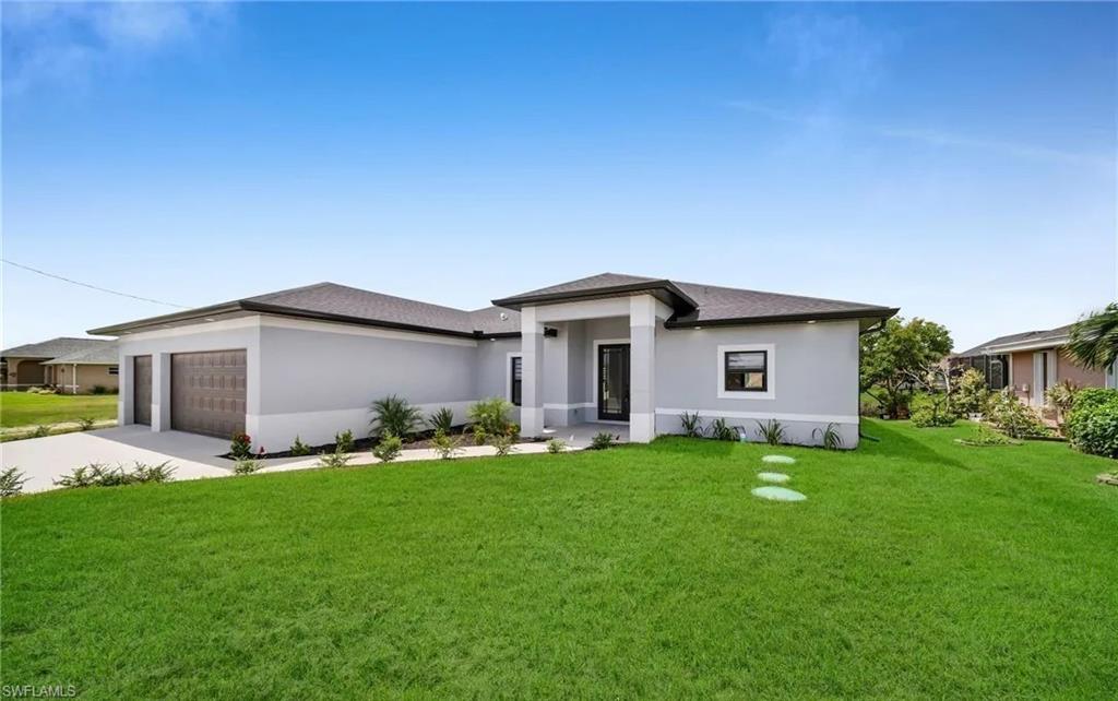 Prairie-style house featuring a front lawn, stucco siding, driveway, and an attached garage